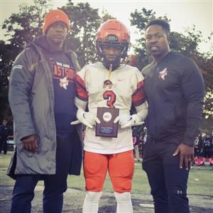 Three males posing or camera. Two adults on the ends and a student in an orange uniform holding a plaque in the middle.